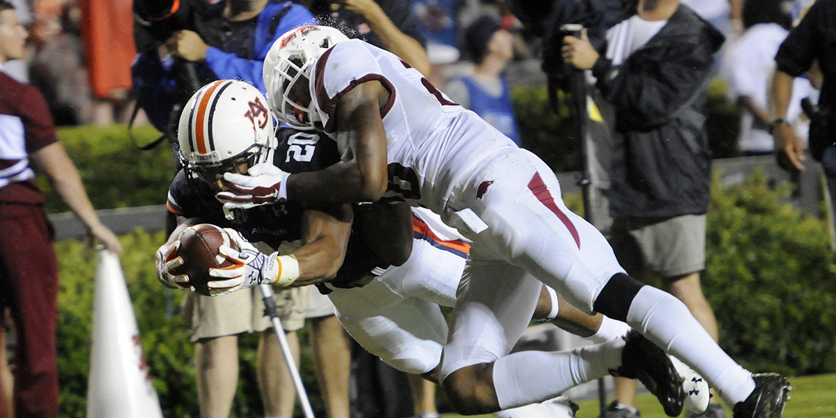 Football player dives with the ball while being tackled